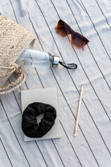 Mockup of diary and pencil, sunglasses, a bottle of water lie on the picnic blanket.