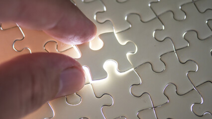 Hand holding jigsaw puzzle last missing piece lighting. 
Concept last piece of jigsaw puzzle for problem and 
completion.