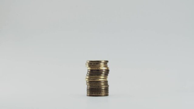 Coins gradually appear on a white background. The tower of them grows, it is not perfectly flat. Stop motion effect is used
