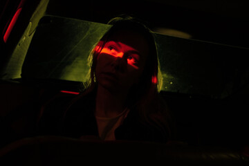 mystical light in the car in the back seat, darkness, contrast, the average plan of the girl in the car