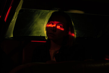 girl's eyes illuminated by red light in the car at night.