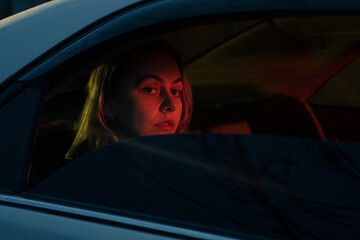 the girl is illuminated by a red light in the car.
