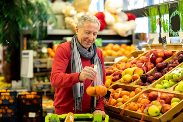 Male customer purchasing at supermarket, choosing fruits