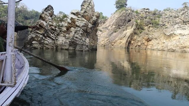 Cinematography view of Bhedaghat through a boat: A stunning perspective of the Narmada River winding between towering marble cliffs, captured from a boat, highlighting the glistening white rocks, flow