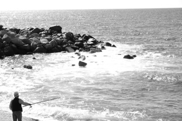 pescatore mare tempesta scogli