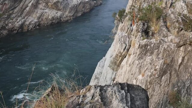 Scenic view of a flowing water stream through mountains at Bhedaghat, Madhya Pradesh: Crystal-clear water meandering between rugged marble cliffs