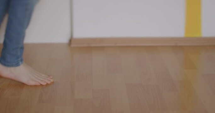 Bare children's feet make a dance move on the floor. He drags his foot across the floor in a step motion. Body coordination training.