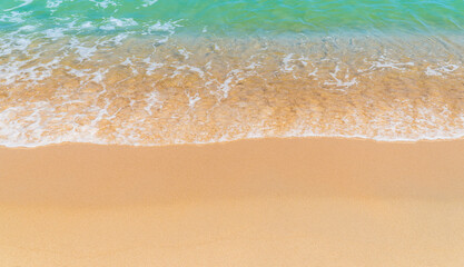 Fototapeta na wymiar Sand beach seaside with white foamy and waves from blue sea on daylight 