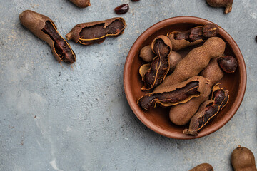 Tropical fruits, Tamarindo beans in shell on a brown butchers block on a dark background, healthy fruit. banner, menu, recipe place for text, top view