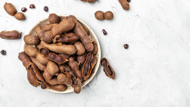 Delicious ripe tamarinds on a wtite plate on a light background, Long banner format. top view