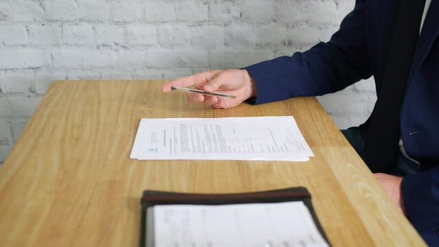 A bored businessman waiting for a meeting spins his pen as he is fidgeting at his desk