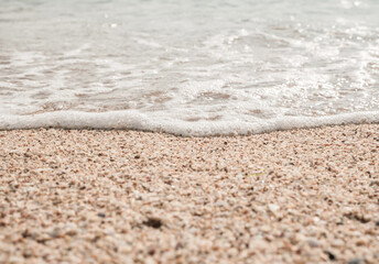 Beach sand sea water summer background. Sand beach desert texture.
White foam wave sandy seashore