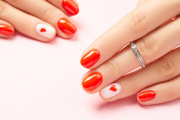 Womans hands with fashionable red manicure on pink background. Valentines day nail design