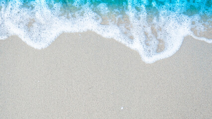 Beach sand sea water summer background. Sand beach desert texture.
White foam wave sandy seashore.  top view