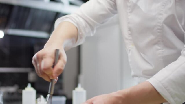 Tilt down shot of Caucasian male chef whisking ingredients in metal bowl while cooking in Bain Marie in restaurant kitchen