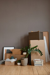 Vertical no people shot of unpacked cardboard boxes and objects placed in loft room against gray wall