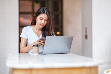 Happy Young Asian woman using a laptop computer at the cafe table Outdoors coffeehouse