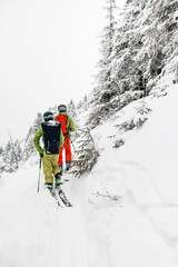 rear view of skiers with backpacks walking on a snow-covered mountain path
