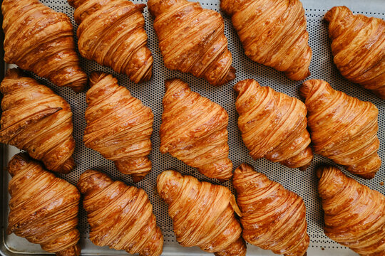 Freshly baked golden French croissants on baking sheet. Fresh classic pastries. Top view . High quality photo