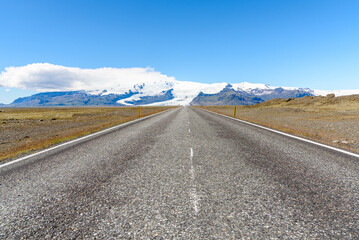 Empty straight road to a glacier on a clear summer day. Southern Iceland.
