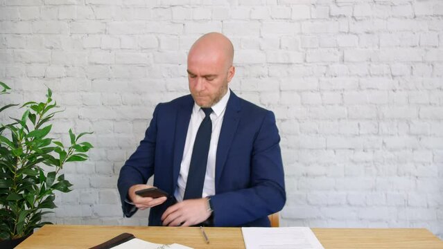 A bored businessman checks his phone at work.