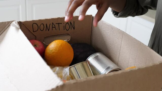 Gloved volunteer collects a box of food for those in need. Social assistance during the coronavirus COVID-19. The concept of social assistance, charity, donation