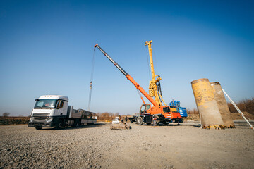 Unloading iron piles from the truck before starting of the construction of a concrete bridge in the field	
