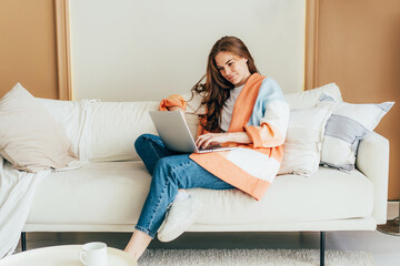 Obraz premium Young Caucasian female freelancer doing her work on laptop from home.