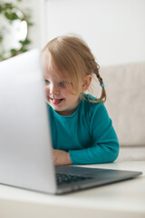 little girl uses a laptop video chat to communicate learning at home, child studying online.