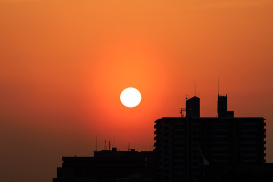 Sun Sets Through Orange Haze Over Silhouetted Buildings