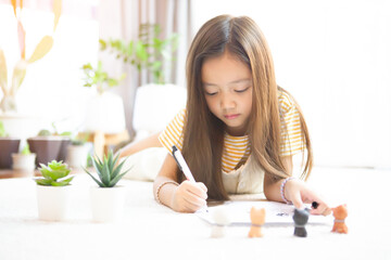 Cute girl with long hair Asian lying on the floor drawing