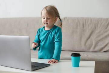 little girl uses a laptop video chat to communicate learning at home, child studying online.