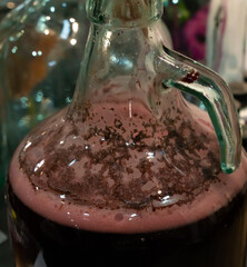 Fermenting wine with bubbles in a glass Carboy during a home brewing process. Close up with shallow depth of field.