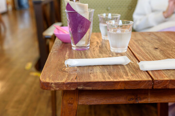カフェ内の木製テーブルに置かれたおしぼりと水、コップ