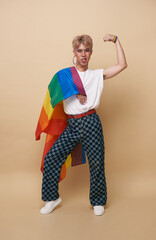 Youth asian transgender LGBT with Rainbow flag on shoulder isolated over nude color background. gender expression pride and equality concept.