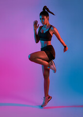 Athlete asian sportswoman running as part of fat burning workout in fitness studio neon background....