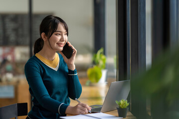 Asian business woman making a phone call and smiling indoor, During break from working in modern office. Mobile business technology concept