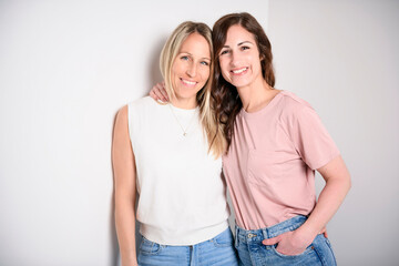 Two smiling best girl friends blond and brunette on white background. Closeup face portrait of two young beautiful women. - obrazy, fototapety, plakaty
