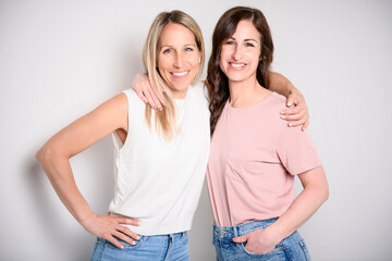 Two smiling best girl friends blond and brunette on white background. Closeup face portrait of two...