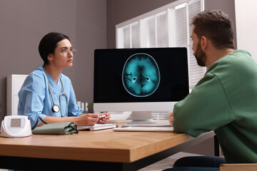 Neurologist consulting patient at table in clinic