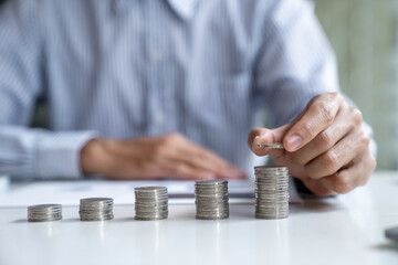 Businessman with a coin in a piggy bank along with pressing the calculator and writing down savings for the future after retirement, ideas for saving money for the future and life after retirement