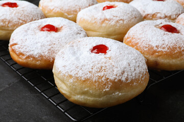 Many delicious donuts with jelly and powdered sugar on black table, closeup