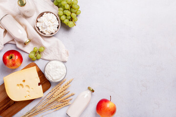 Shavuot flat lay with dairy products, first fruits and wheat on light gray background