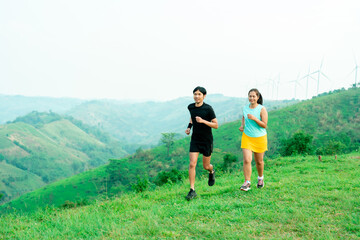 Obraz premium couple Asian man and female trail runners. Wearing sportswear practicing on a trail running in the mountains behind a beautiful mountain on a clear day. Practice running happily