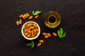 Obraz na płótnie Canvas Sweet almond oil in glass jar and almond seeds with green leaf