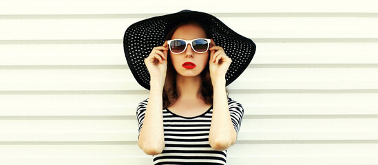 Portrait of beautiful woman model wearing black round summer hat, striped dress on white background