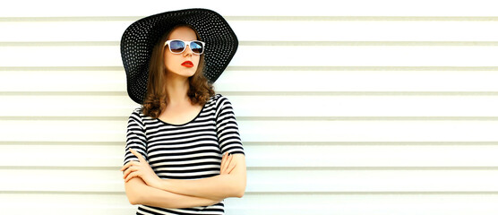 Portrait of beautiful woman model wearing black round summer hat, striped dress on white background