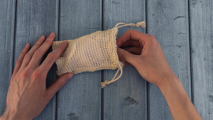 woman hand pulls reusable organic cotton pad out of knitted eco bag. zero waste cosmetic and hygiene accessory. sustainable lifestyle concept. © kotograf