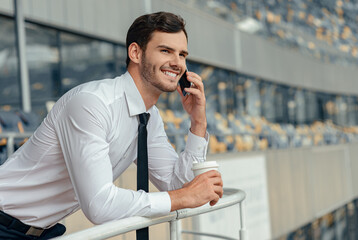 Happy young businessman in white shirt calling by smartphone