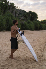 Sexy surfer surfing man with surfboard. Handsome young male athlete holding surf board with wet hair on summer beach sport holiday. Sports travel destination. Surfing lifestyle.